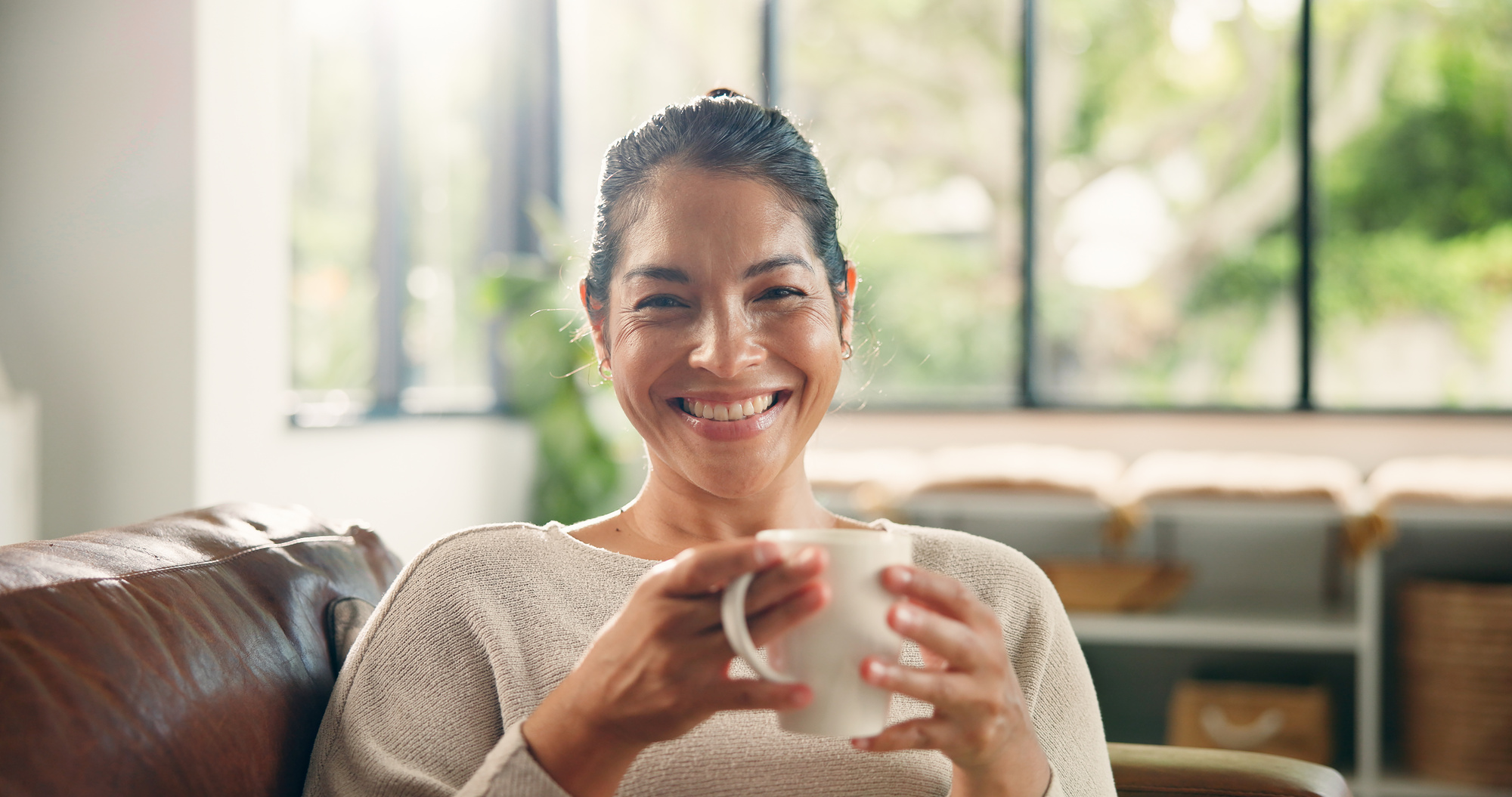 coffee_home_and_portrait_of_happy_woman_on_sofa_with_drink_for_wellness